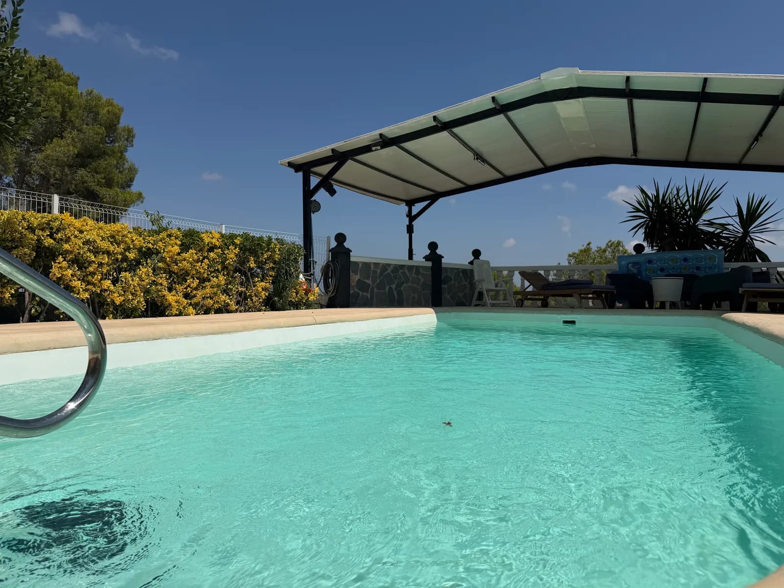 Agua turquesa de la piscina salina de Ryfugio con la pérgola y el seto en flor