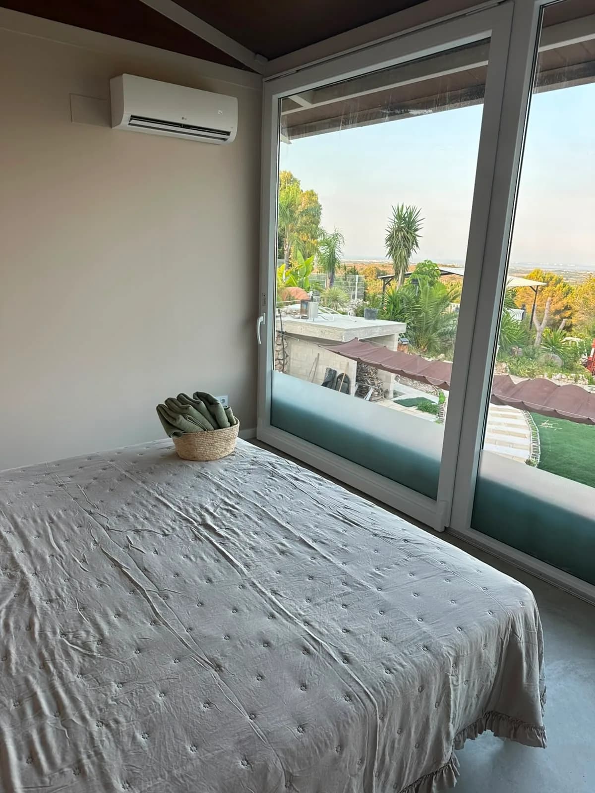 Cama del dormitorio principal junto a un ventanal con vistas exteriores