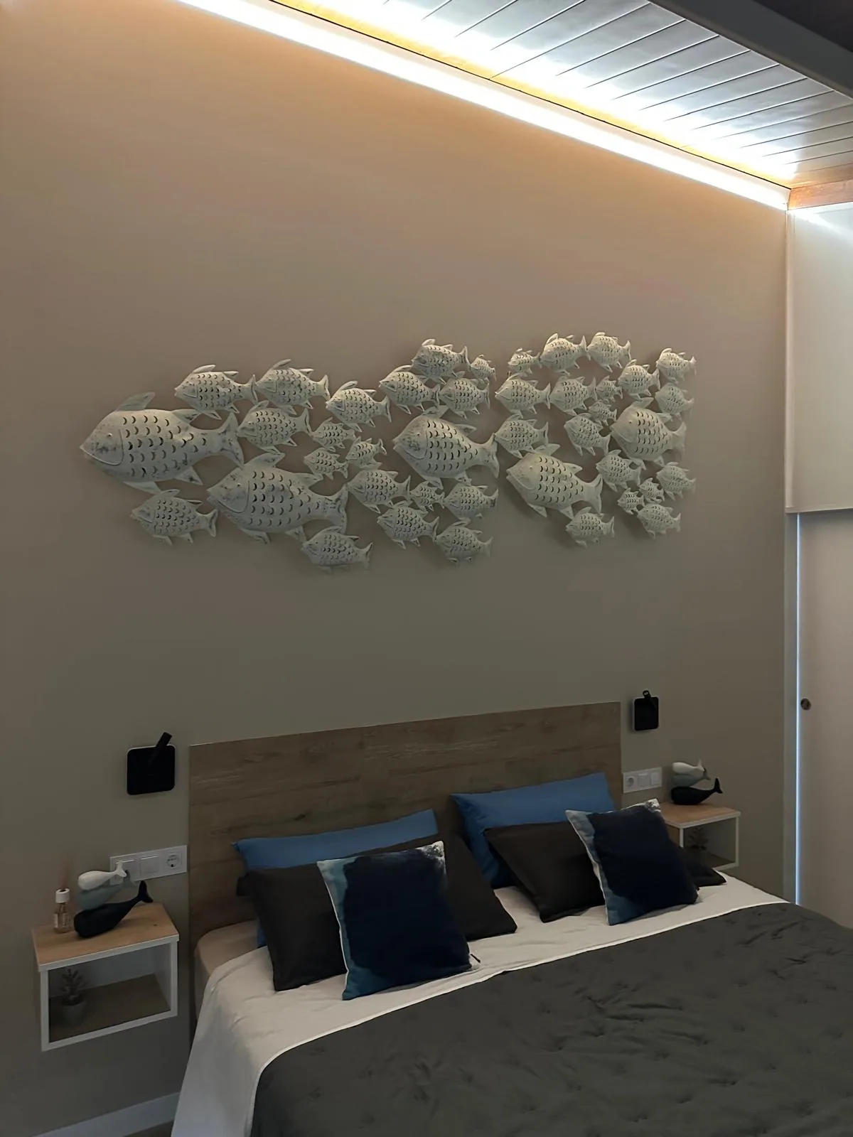 Segundo dormitorio con cama doble y composición decorativa de peces