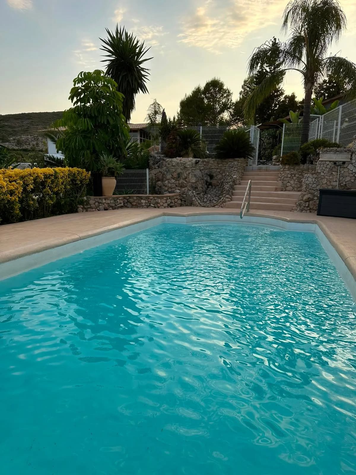 La piscina al atardecer con el jardín alrededor