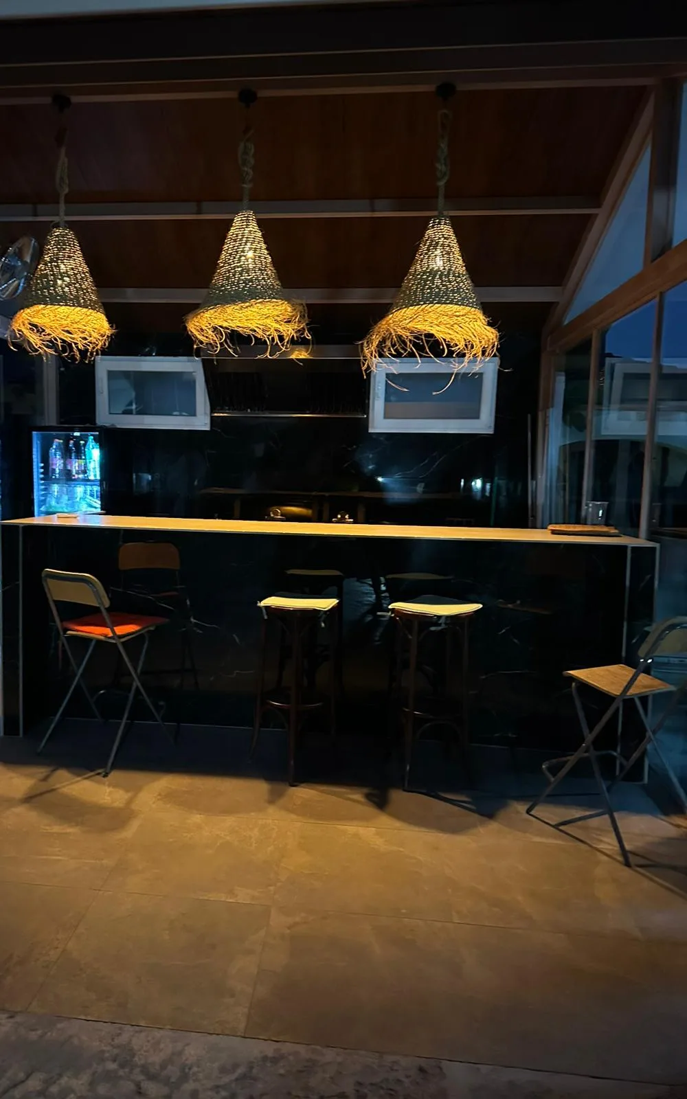 Barra con campana extractora y zona de cocina exterior encendida al anochecer