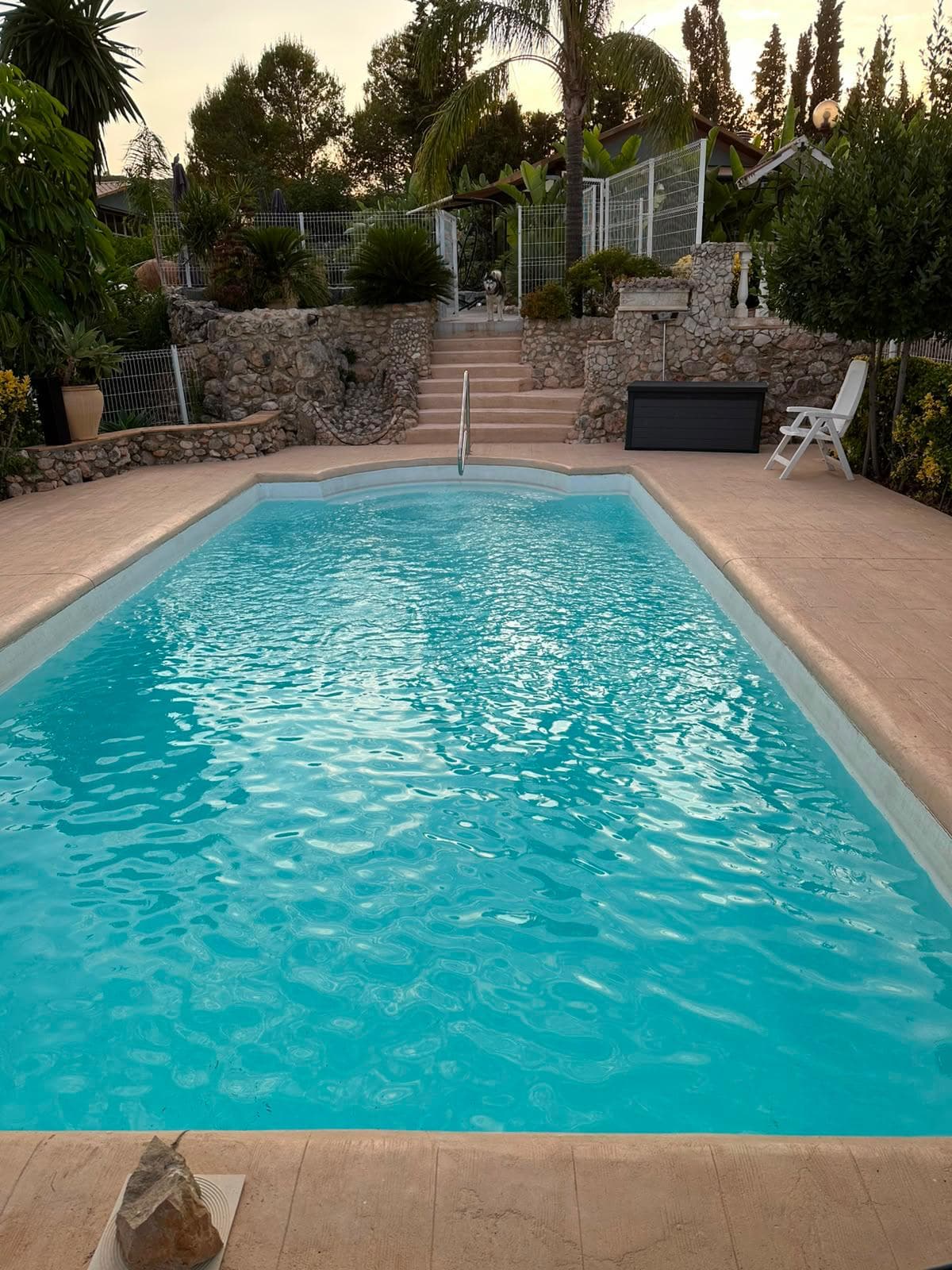 La piscina de Ryfugio al atardecer, con la escalinata de piedra y el jardín detrás